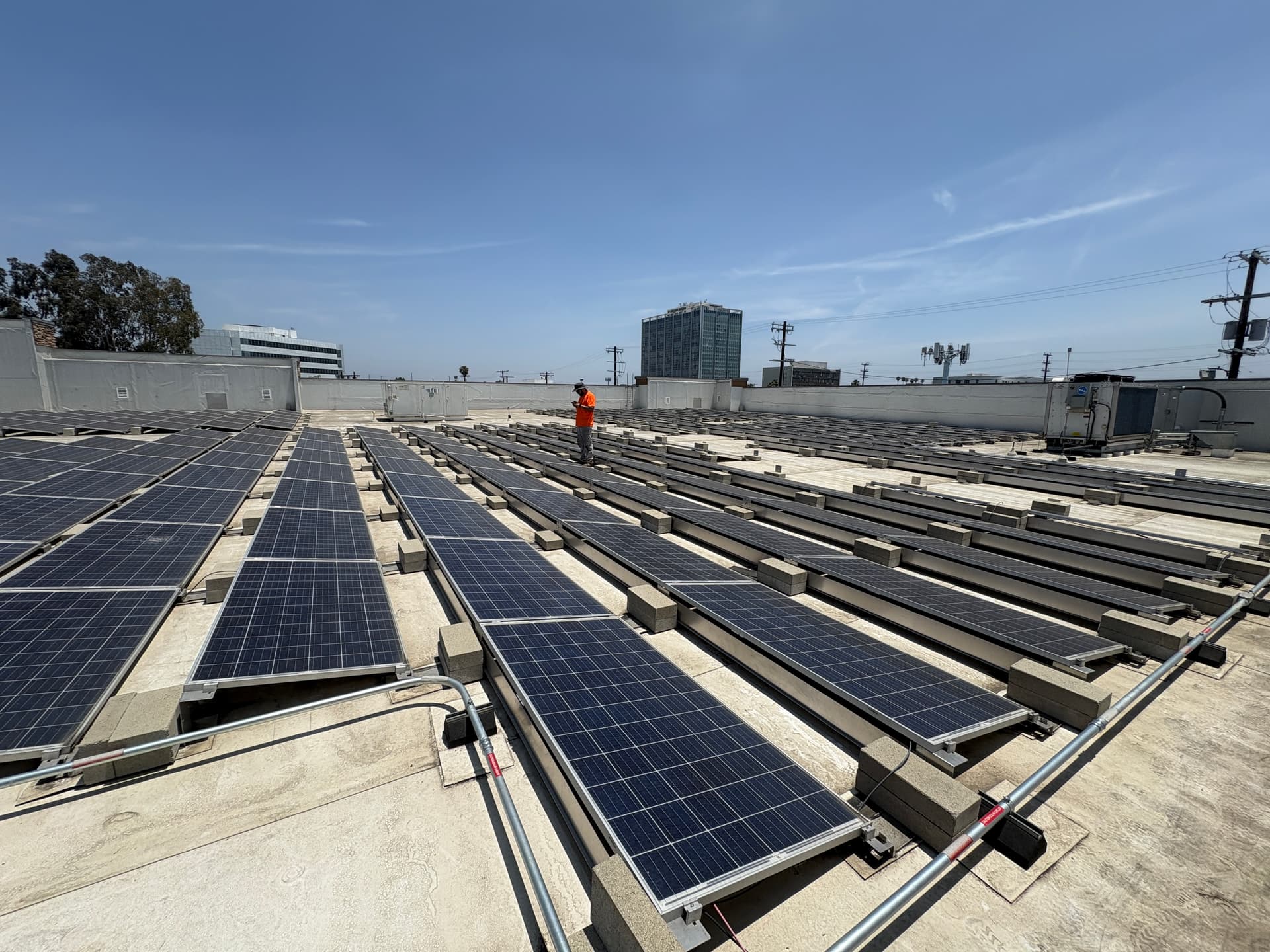 RCH technician documenting rows of ballasted solar panels during a flat-roof commercial site inspection